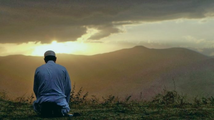 Мужчина совершает намаз в поле Мужчина совершает намаз в поле